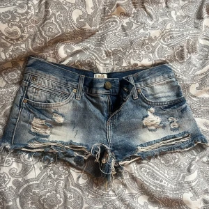 Blå slitna jeansshorts från River Island - Säljer ett par blå jeansshorts från River Island med slitna detaljer och fransig kant. Shortsen har låg midja, har tyvärr inga bilder med dom på då dom var förstora när jag köpte dom💕 pris går att diskuteras💕