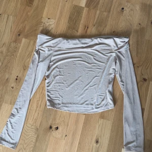 Beige offshoulder topp - Trendig beige offshoulder topp med långa ärmar. Tunn och mjuk i materialet, perfekt för en stilren look. Storlek s