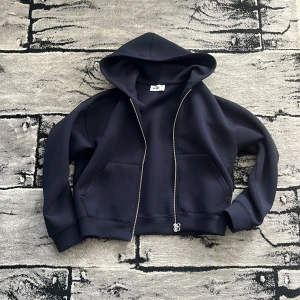 Mörkblå scuba hoodie från Weekday - Tröjan har dubbelsidig dragkedja framtill, huva och två stora fickor. Avslappnad form i scuba-materiel. Nyskick, använd ett par gånger. Meddela vid intresse, pris kan diskuteras. 