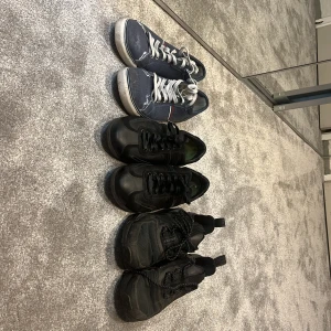 Tre par sneakers, varav ett par Adidas - Säljer tre par sneakers: ett par blå med vita snören och detaljer, ett par helsvarta Adidas och ett par helsvarta sneakers utan synligt märke. Perfekta för vardagsbruk och enkel stil. Skriv privat för pris på de olika skorna. Paketpris på alla 400 Adidas skorna är Strl 42 passar 43 dem andra är 44