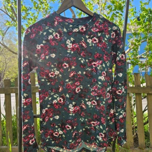 Blommig långärmad tröja i grönt och rött - Säljer en långärmad tröja med blommigt mönster i rött, vitt och grönt. Tröjan har rund halsringning och är perfekt för dig som gillar färg och mönster. Superfin till jeans eller kjol!