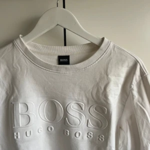 Vit sweatshirt från Hugo Boss - Säljer en stilren vit sweatshirt från Hugo Boss med upphöjd logga framtill. Tröjan har rund halsringning och långa ärmar. Perfekt för en clean och klassisk look. Storlek M men sitter mer som S.     Pris kan diskuteras vid snabb affär