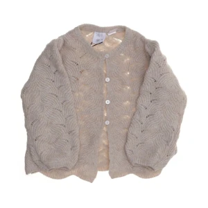 Beige stickad kofta med mönster - Superfin beige stickad kofta från MP Denmark med rund hals och dekorativa knappar framtill. Koftan har ett vågigt mönster och ballongärmar som ger en trendig look. Perfekt att slänga på sig över en topp.