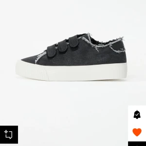 Svarta sneakers med fransade kanter och kardborreband - Säljer ett par svarta sneakers med vit sula och coola fransade kanter. Skorna har tre breda kardborreband för enkel påtagning och en avslappnad streetstil. Perfekta för dig som gillar en lite ruffare look.