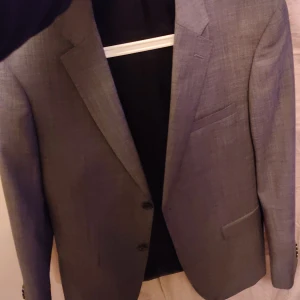 Grå kavaj herr Bläck - Snygg grå kavaj med klassisk passform. Perfekt för en stilren look inför skolavslutningen/studenten. Aldrig använd. Nypris c.a 2000 pris kan diskuteras vid snabb affär