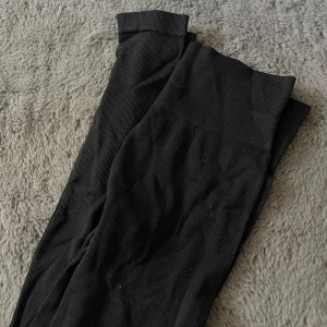 Svarta ribbade leggings - Svarta leggings med ribbad struktur och hög midja. Mjukt och stretchigt material som sitter skönt på kroppen. Perfekta för en avslappnad stil eller till träning.