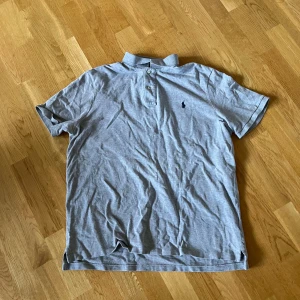 Grå piké- Ralph Lauren - Säljer en klassisk grå pikétröja från Polo Ralph Lauren med liten broderad logga på bröstet. 