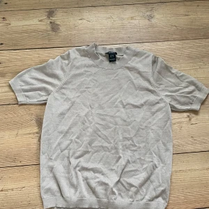 Beige kortärmad tröja från Lindex - Säljer en stilren beige kortärmad tröja från Lindex i storlek XS. Tröjan har rund halsringning och är tillverkad i ett mjukt, tunt material som passar perfekt till varmare dagar.