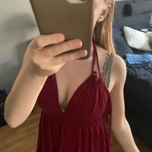 Vinröd omlottklänning med volang - Säljer en vinröd kortklänning med halterneck och omlottdesign. Klänningen har volangdetaljer och knyts i nacken. Perfekt för sommarens tillfällen och har en luftig, flowy passform. Köpte den utomlands så märket är ej hm men behövde välja ett. Den är kort i storleken.