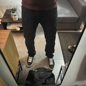 Svarta Levis 501 jeans - Säljer ett par svarta Levis 501 jeans med klassisk rak passform och knappgylf. Byxorna är i denim och har en tidlös look som passar till det mesta. Märkespatch bak i midjan. Perfekta för dig som gillar stilrena jeans.