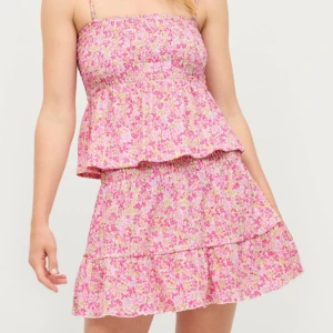 Blommig sommarklänning med volang - Sött blommigt set  i rosa, vit och grönt med smock upptill och volangdetaljer. Toppen saknar axelbanden men är tänkt att kunna bäras utan som en bandeu- topp