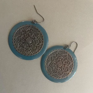 Stora runda örhängen med blå kant - Säljer ett par stora runda örhängen med blå kant och detaljerat metallmönster i mitten. Örhängena har en vintagekänsla. 