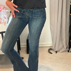 Blå bootcut jeans med snörning Guess - Snygga blå bootcut jeans från guess. Snygg detalj med snörning. Jag är 175 cm lång. Inneben måtten är 89 och W26 