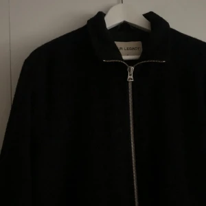 Our Legacy jacka - Stilren svart jacka från Our Legacy med rak passform och hel dragkedja framtill. Jackan har minimalistisk design som funkar till många olika looks. Perfekt för dig som gillar enkel men snygg stil. Jackan är använd men i bra skick. Storlek 48, sitter som en Medium.
