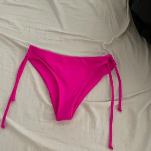 Chockrosa bikini från SHEIN med knyt - Snygg chockrosa bikini från SHEIN i klassisk modell med knyt i sidorna. Tillverkad i stretchigt material som sitter skönt och formar sig efter kroppen. Perfekt för strandhäng och poolparty. Enkel och stilren design som verkligen poppar i färgen.