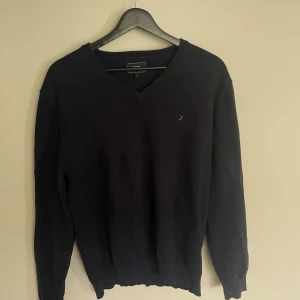 Mörkblå v-ringad tröja Boomerang  - Klassisk mörkblå v-ringad tröja från Boomerang med diskret broderad logga på bröstet. Tröjan har långa ärmar och är tillverkad i mjuk bomull, perfekt för lager-på-lager-stil under kyliga dagar.