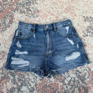 blå jeansshorts Pull&Bear - Snygga blå jeansshorts från Pull&Bear med hög midja, slitna detaljer och fransig kant. Priset kan diskuteras!