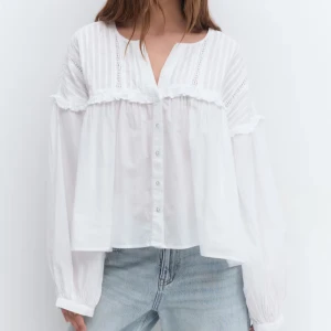 Vit blus med spets och knappar - Supersöt vit blus med v-ringning, knappar framtill och fina spetsdetaljer på axlar och bröst. Långärmad och luftig passform som ger en romantisk vibe. Perfekt att styla med jeans för en chill look.