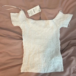 Vit offshoulder topp från Zara S - Superfin vit offshoulder topp från Zara i storlek S. Säljer då den inte kommer till användning. Köpte för 200kr men har aldrig använts.