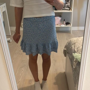 Blommig blå volangkjol från Lindex  - Blå blommig kjol från Lindex. Storlek 134/140 men passar xs. Bra skick. 80kr