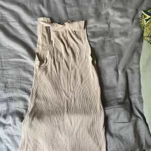 Beige ribbad ärmlös klänning från Zara - Säljer en beige ribbad klänning från Zara. Den är ärmlös med djup v-ringning och har en tight passform som framhäver figuren. Perfekt för varma dagar och enkel att styla med sneakers eller sandaler.