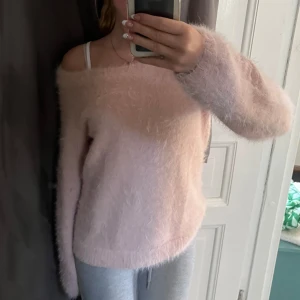 Ljusrosa tröja - Supermjuk och fluffig ljusrosa tröja med offshoulder-design. Långärmad och oversized känsla, perfekt för dig som gillar en cozy och trendig stil. Materialet är lurvigt och ger en riktigt mysig vibe💗