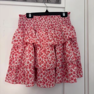 Rosa blommig volangkjol - Supersöt kort kjol med flera volanger och blommigt mönster i rosa och vitt. Kjolen är från vinted sen innan och det står tyvärr inget märke men storlek XS 💕bra skick!