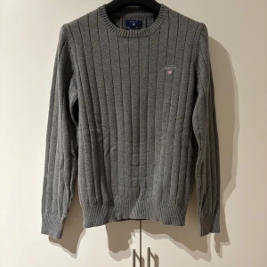 Grå ribbstickad tröja från GANT - Snygg grå ribbstickad tröja från GANT. Perfekt för dig som gillar stilren och enkel design. Hör av dig vid frågor! 
