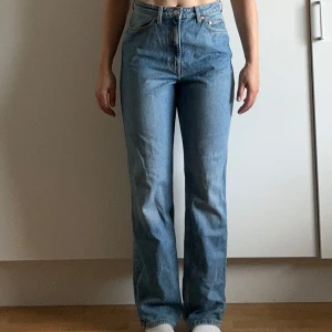 Weekday Rowe ljusblå raka jeans - Säljer ett par Weekday Rowe Extra High Straight Jeans i ljusblå tvätt. Jeansen har hög midja, raka ben och klassisk femficksdesign. Tillverkade i bomull med snygga kontrastsömmar och Weekday-lapp bak i midjan. Perfekta för en clean och avslappnad look.