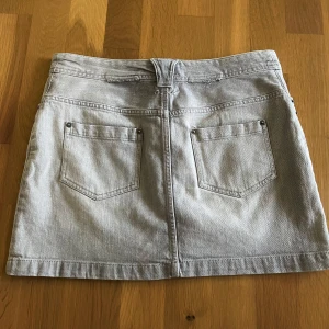 Ljusgrå jeanskjol med fickor - Snygg ljusgrå jeanskjol med bälteshällor och knapp framtill. Kjolen är kort och har raka linjer. Skriv om frågor! :)