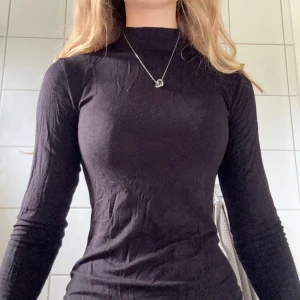 Svart polotröja med lång ärm - Säljer en svart stretchig polotröja med lång ärm och tight passform, lite see through.