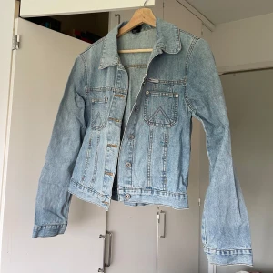 Klassisk ljusblå jeansjacka - Snygg ljusblå jeansjacka med klassisk krage och två bröstfickor med knapp. Jackan har raka ärmar och knäppning framtill med metallknappar. Perfekt för att slänga över en hoodie eller t-shirt för en chill look.