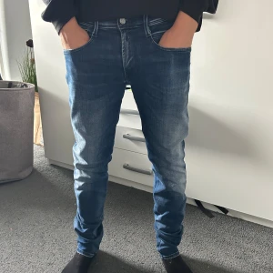 Replay Anbass Hyperflex Slim Fit - Säljer ett par Replay Hyperflex jeans i klassisk blå tvätt. Jeansen har normal passform, raka ben och snygga slitningar framtill. Stretchigt material för extra komfort och snygg look. Perfekta för dig som gillar stilrena och bekväma jeans. Pris går att diskutera!
