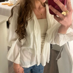 Vit blusig skjorta från POUR - Säljer en as snygg vit blusig skjorta från POUR som är super fin att ha både stängd och öppen över någon gullig topp!💗Tröjan är i skönt tunn bomulls material. Står ej storlek men skulle säga att den är i storlek S men ska sitta lite flowy🫶