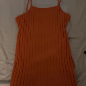 Ribbad orange klänning från SHEIN - Snygg ribbad orange klänning från SHEIN med smala axelband och rak halsringning. Klänningen är kort och har en figurnära passform, perfekt för varma dagar. Enkel och stilren design som är lätt att matcha med accessoarer. Säljer då den inte passar mig längre🩷