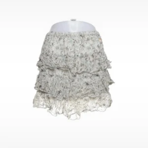 Beige volangkjol med spetsdetaljer - Supersöt kort volangkjol i beige med ljusa toner och spetsiga detaljer. Kjolen har flera lager volanger som ger en fluffig och lekfull look. Perfekt för dig som gillar romantisk och bohemisk stil.