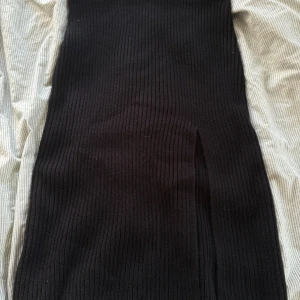 Svart ribbad långklänning NLY Trend - Svart långklänning från NLY Trend i ribbstickat material. Klänningen har en tight passform och en slits framtill för extra edge. Perfekt för dig som gillar minimalistisk och stilren look.