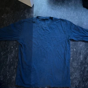 Mörkblå långärmad tröja - En basic mörkblå långärmad tröja i mjukt bomullsmaterial. Enkel och clean design med rund halsringning, perfekt att styla med jeans eller under en jacka. Passformen är normal och tröjan har inga synliga detaljer eller mönster.