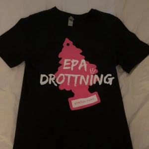 Svart EPA Drottning t-shirt S - Svart t-shirt med stor rosa text 'EPA DROTTNING' samt 'STRÖGA RUNT' på bröstet. Skön passform. Perfekt för dig som vill sticka ut eller gillar raggarlivet. Säljer då jag knappt använder sådana här kläder längre men tycker själv det är mycket snyggt att gå runt med! Passar både S och M. 