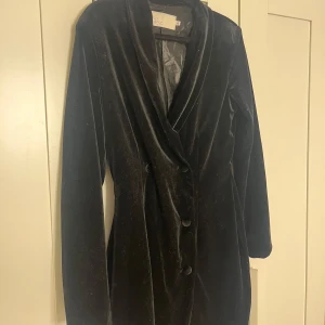 Svart sammetsklänning från NLY Trend - Snygg svart sammetsklänning från NLY Trend i kort modell. Klänningen har långa ärmar, djup v-ringning och knappar framtill som ger en cool blazer-look. I mycket bra kvalite och ordentligt material💗 skriv för fler frågor om mått eller annat🫶