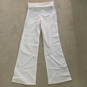 Vita utsvängda linnebyxor från H&M - Snygga vita linnebyxor från H&M med låg midja och vida ben. Byxorna har en mjuk, stretchig linning och är tillverkade i ett lätt och luftigt linnematerial. Helt nya med prislapp. Säljer då dem tyvärr var för små🥺