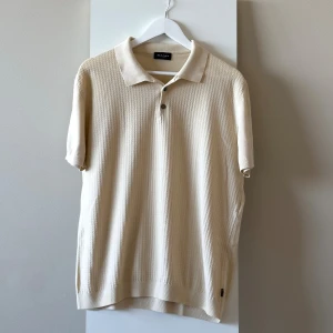 Beige pikétröja från Sand Copenhagen (L/XL storlek) - En tunn beige pikétröja från SAND. Perfekt för en clean och laidback stilren look. Passar bra på sommaren. Använd ett fåtal gånger men ser ut som ny, inga defekter. 100% Bomull. Storlek är XL men funkar även som en L. Nypris 500 kr.