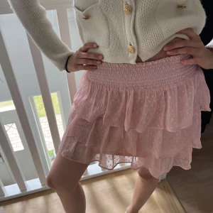 Rosa volangkjol med prickigt mönster - Supersöt kort rosa kjol med flera lager volanger och diskret prickigt mönster. Storlek 146/152 men passar XS (personen på bilden är 170cm)