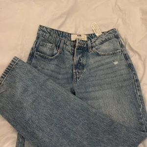 Blå raka jeans från STR Teen - Snygga ljusblå jeans från STR Teen med klassisk femficksdesign och raka ben. Jeansen har medel midja och är tillverkade i bomull med en cool tvättad look. Perfekta för en avslappnad och trendig stil. Ny utan prislapp!