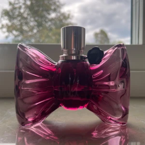 Viktor & Rolf Bonbon parfym - Säljer en ikonisk Viktor & Rolf Bonbon parfym i en snygg mörkrosa glasflaska formad som en rosett. Flaskan har en silverfärgad spraykork och svart logodetalj. Perfekt för dig som gillar söta och lyxiga dofter.Ungefär hälften kvar💕 Ny pris 1450kr