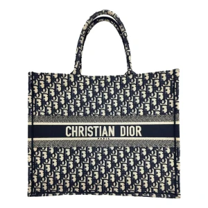 Christian Dior Boktota väska  - Snygg och rymlig Boktota väska från Dior i svart och vitt canvasmaterial med ikoniskt monogrammönster. Väskan har två handtag, rektangulär form och tydlig logga framtill. Perfekt för att bära allt du behöver och ger en lyxig vibe till din outfit. 