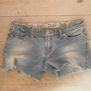 D&G ljusblå jeansshorts  - Snygga ljusblå jeansshorts från D&G med slitna detaljer och rå, fransig kant. Broderade bakfickor 