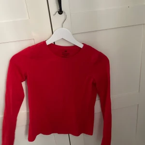 Röd långärmad tröja från H&M - En enkel och stilren röd långärmad tröja från H&M. Tröjan har rund halsringning och är gjord i mjuk bomull, perfekt att matcha med jeans eller kjol för en clean look.