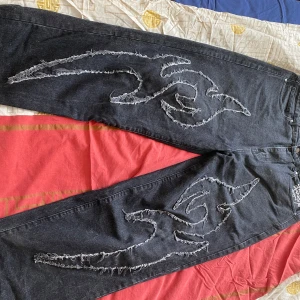 Ed Hardy x Urban Outfitters jeans - Jeans från Ed Hardy med slitna mönster längs benen och vit Ed Hardy-logga på bakfickan. Raka ben och loose fit.