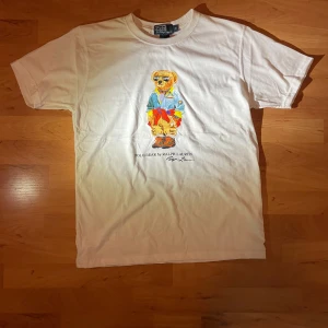 Polo bear - Polo Bear T-shirt – Vit, Storlek M • Helt ny, aldrig använd • Klassisk vit färg • Perfekt skick, autentisk Polo Bear-design • Bekväm och snygg för vardagsbruk • Bra pris: endast 24 €!  Köp den innan den är slut! Fråga gärna om du vill ha fler bilder eller detaljer.